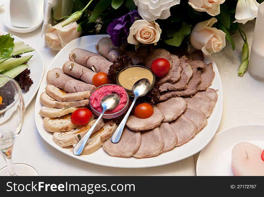 Sliced meat with mustard, horseradish and tomatos on a plate