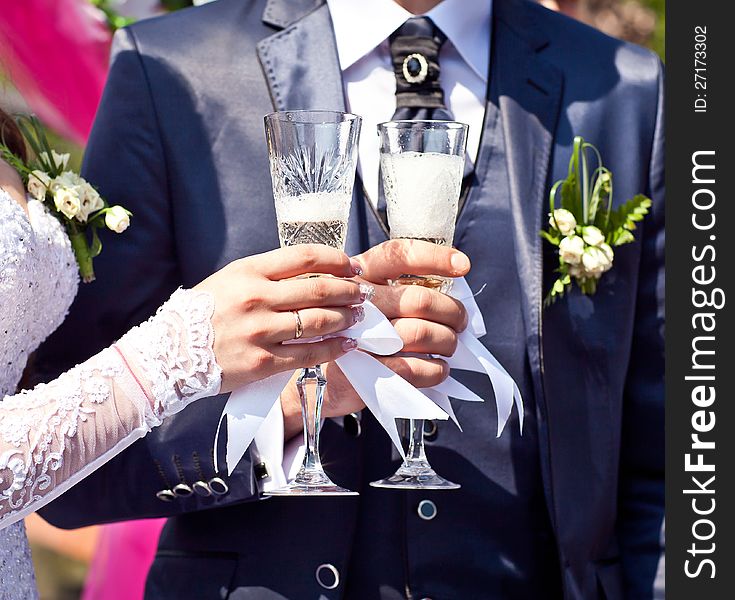 Glasses with champagne in hands newlyweds