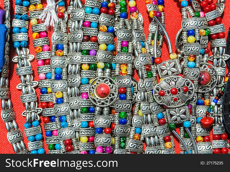 Colorful decorative stone with silver bracelet of hill tribe in northern of thailand on red background.