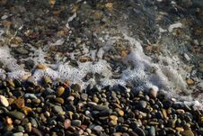 Crystal Clear Water On The Seashore. Sea Foam From Small Waves. The Beach Is Lined With Small Colorful Pebbles. Stock Images Crystal Clear Water On The Seashore. Sea Foam From Small Waves. The Beach Is Lined With Small Colorful Pebbles. Stock Images