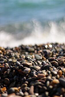 Small Multicolored Pebbles On The Beach In Macro. Sea Foam From Small Waves. Royalty Free Stock Photography