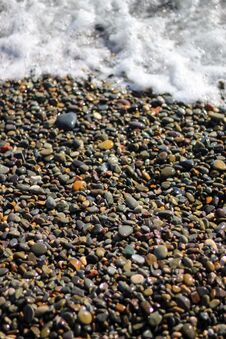 Wet Stones By The Sea .The Beach Is Linked With Small Colorful Pebbles. Sea Foam From Small Waves. Stock Photography