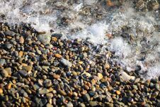 Splashing Waves On The Seashore. The Beach Is Made Of Small Colorful Pebbles. Sea Water Splashes Hitting The Stones. Royalty Free Stock Photos