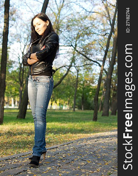 Low angle view of a modern attractive trendy young woman standing on a paved walkway in the country. Low angle view of a modern attractive trendy young woman standing on a paved walkway in the country