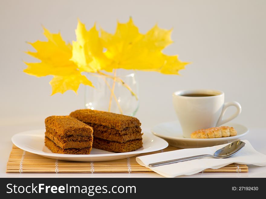 Coffee cup and sweet cake with autumn leaves onbamboo