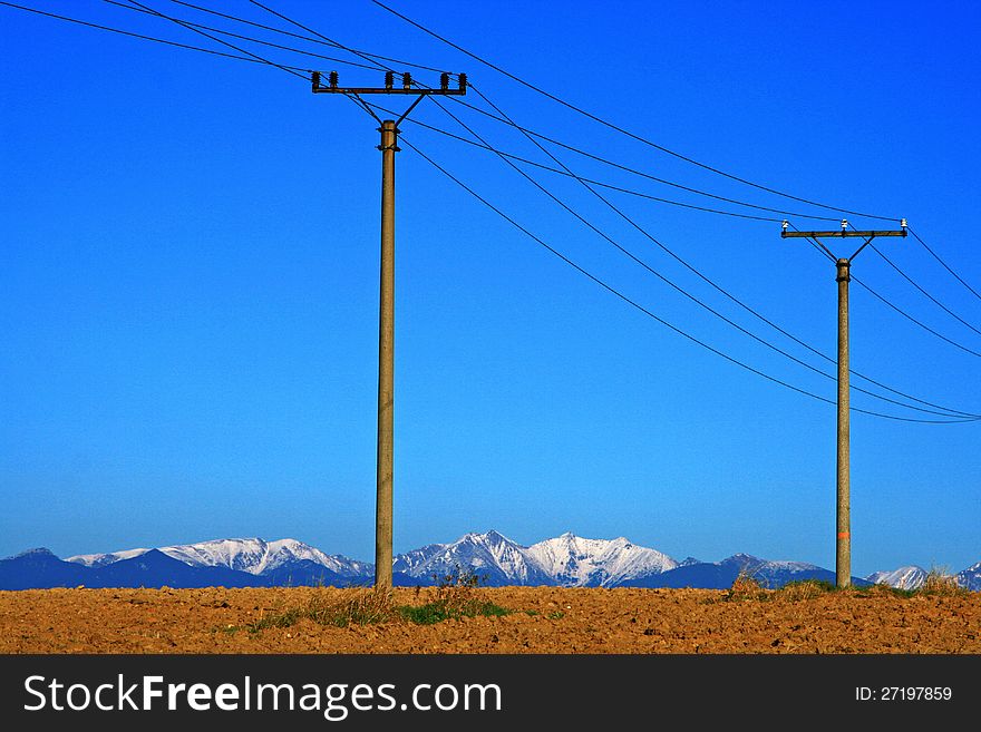 Electric power transmission on field in city Ruzomberok, Slovakia - High Tatras mountains in backround