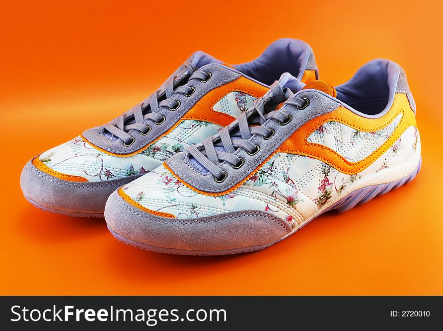 A couple of casual fashionable woman footwear on a orange background. A couple of casual fashionable woman footwear on a orange background