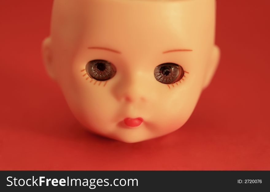 A close up of a doll's head on a red background. A close up of a doll's head on a red background