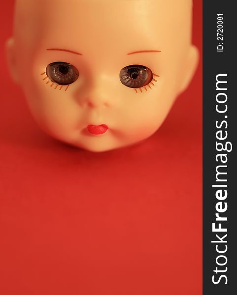 A close up of a doll's head with a red background. A close up of a doll's head with a red background