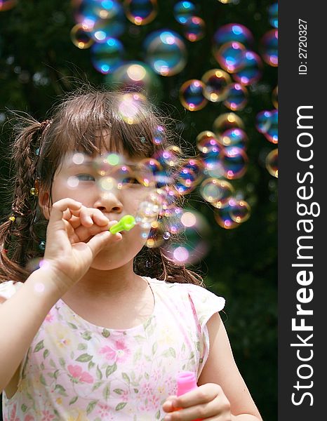 Girl blowing colorful big soap bubbles. Girl blowing colorful big soap bubbles