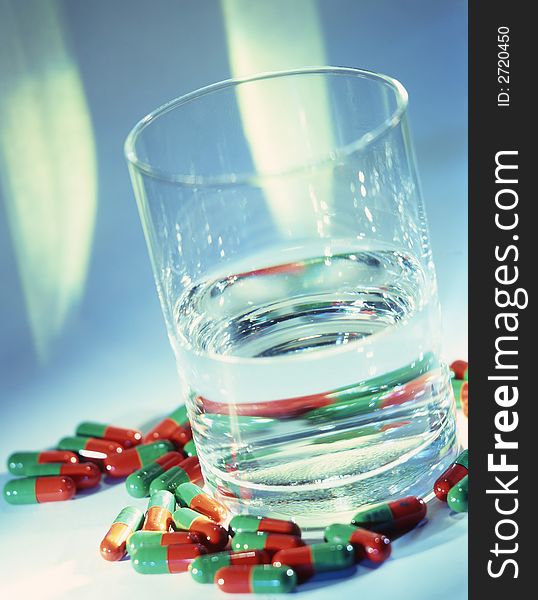 Glass with water and tablets on a blue background . Glass with water and tablets on a blue background