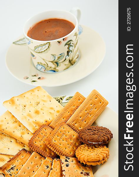 A plate of assorted biscuits with crackers and a cup of hot chocolate drink. A plate of assorted biscuits with crackers and a cup of hot chocolate drink