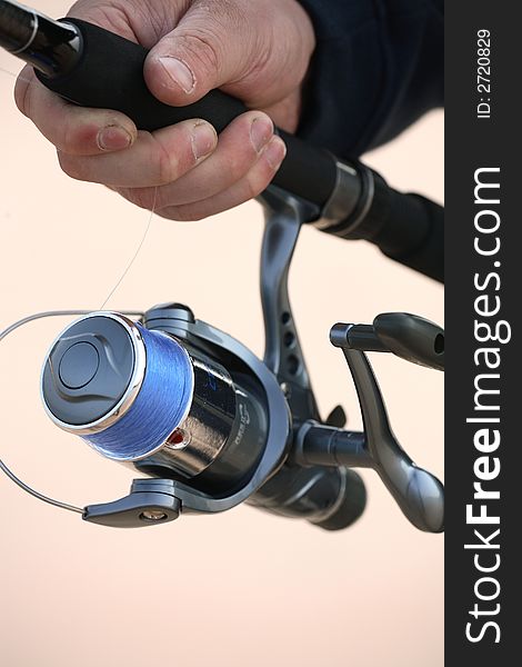 A close up shot of a hand holding a fishing rod. A close up shot of a hand holding a fishing rod