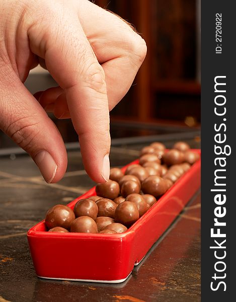 Man's hand reaching for some chocolate crunchy mini balls. Man's hand reaching for some chocolate crunchy mini balls