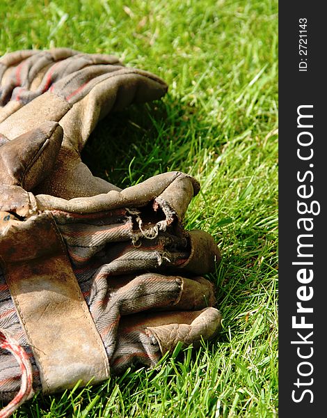 A pair of old and worn garden gloves laying on the lawn.