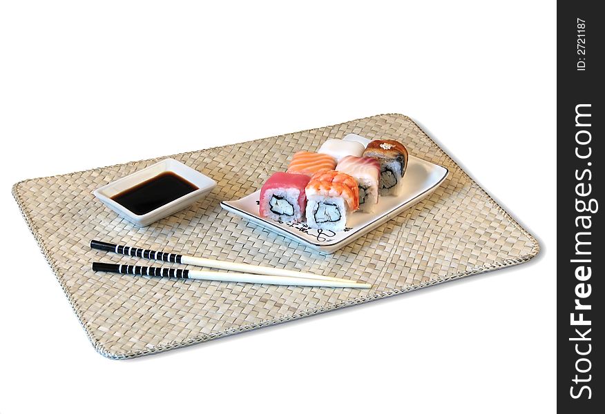 Sushi, soya sauce, chopsticks are located on bamboo mat. Sushi, soya sauce, chopsticks are located on bamboo mat