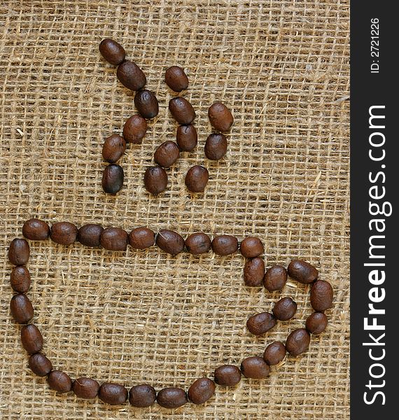 Outline of coffee cup made from coffee beans over burlap background