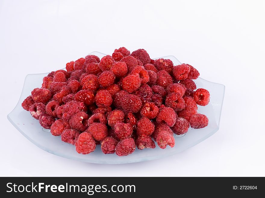 Raspberries on a glass plate on the  white  background