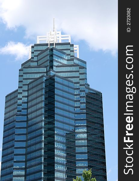 A modern blue office tower rising into clouds. A modern blue office tower rising into clouds