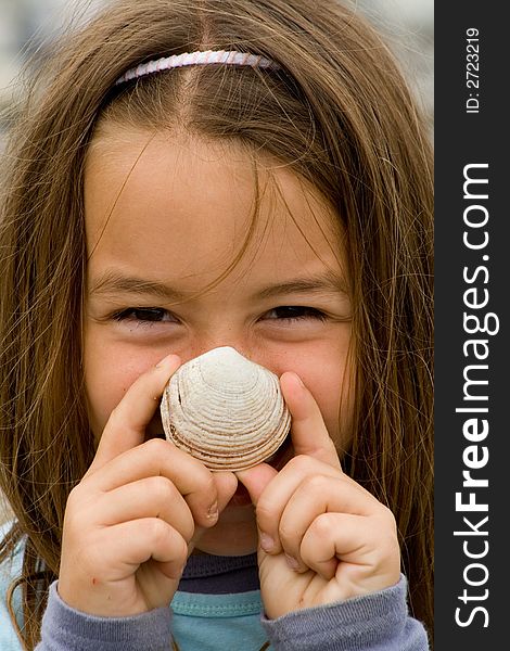 A Happy Young Girl holding seashell over her nose. A Happy Young Girl holding seashell over her nose.