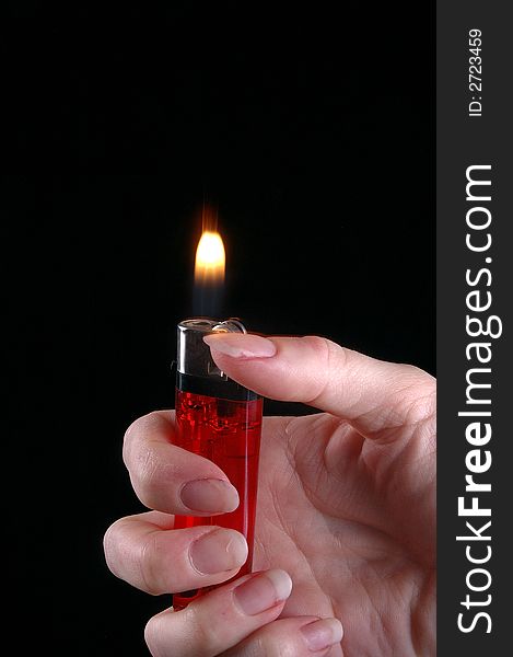 A hand holds a cigarette lighter. Black background.