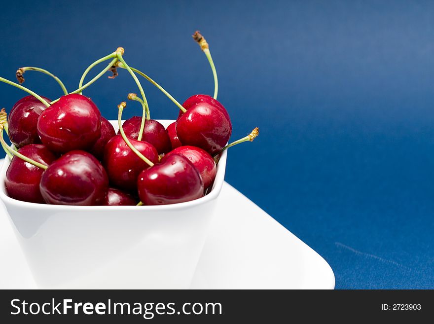 Multiple moist red cherries in a white bowl. Multiple moist red cherries in a white bowl