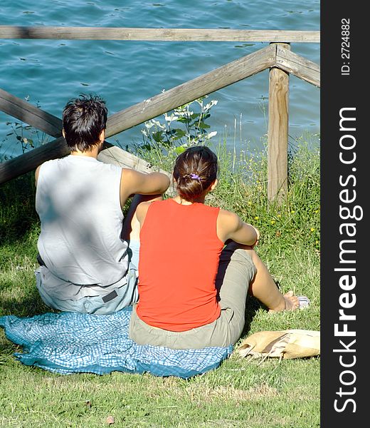Young couple relaxing on the grass in the park, in front of the lake. Young couple relaxing on the grass in the park, in front of the lake
