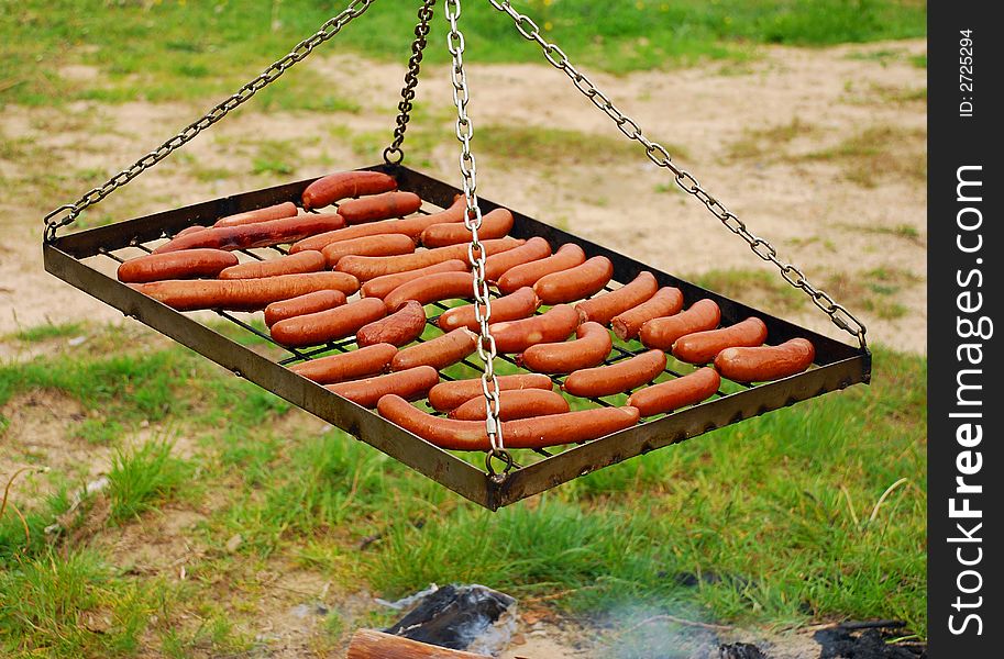 Metal grill full of fried sausages in the country. Metal grill full of fried sausages in the country