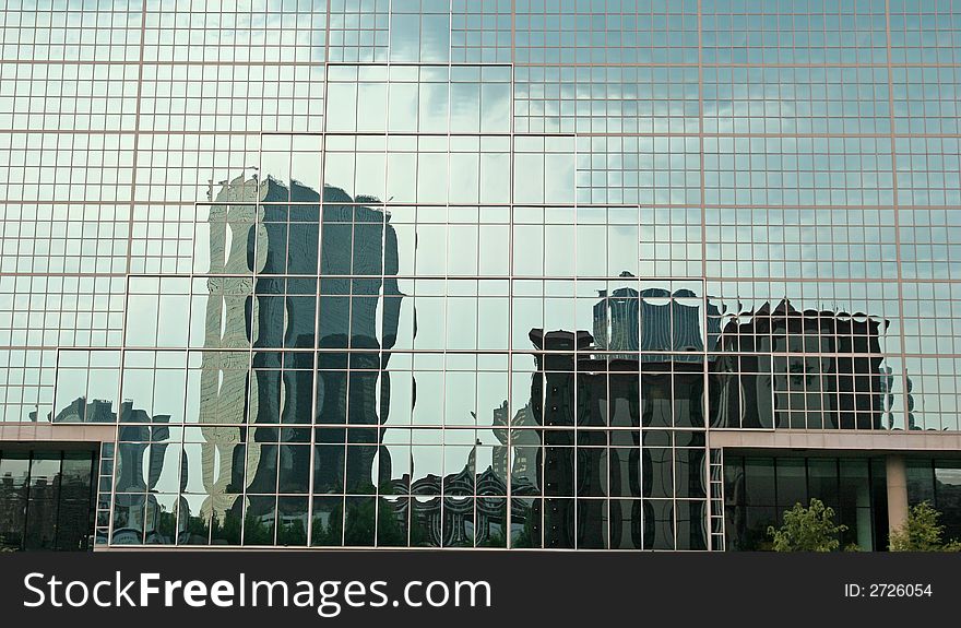 Office buildings reflected in a blue glass building. Office buildings reflected in a blue glass building