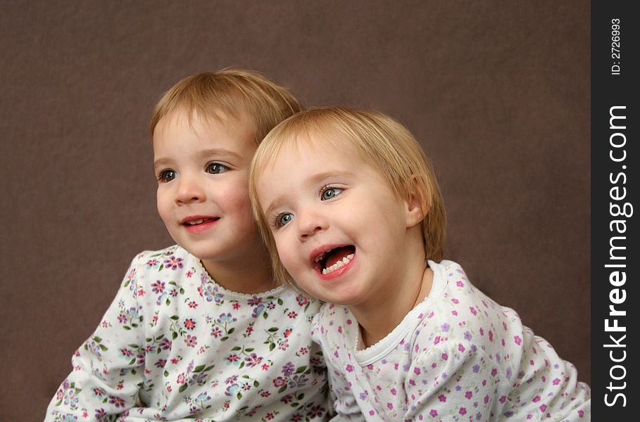 Twin sisters laugh at an onlooker during a photo session. Twin sisters laugh at an onlooker during a photo session.