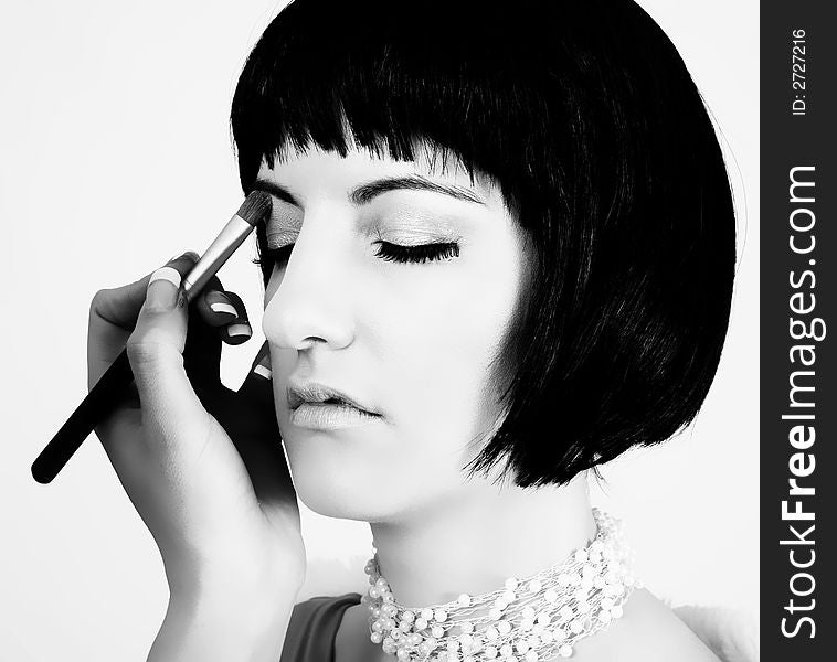 Black & white portrait of a woman having cosmetics applied on her  right eye lid. Black & white portrait of a woman having cosmetics applied on her  right eye lid