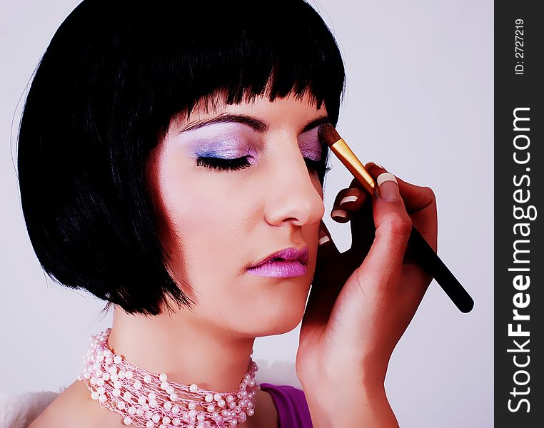 Portrait of a beautiful brunette woman being made up by make-up artist. Portrait of a beautiful brunette woman being made up by make-up artist