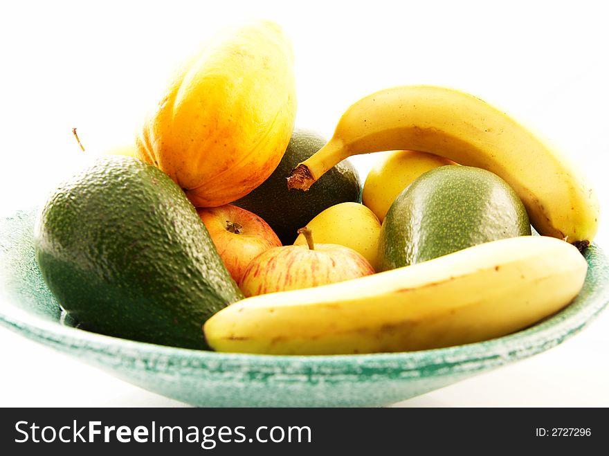 Green bowl of fresh fruit on a white background