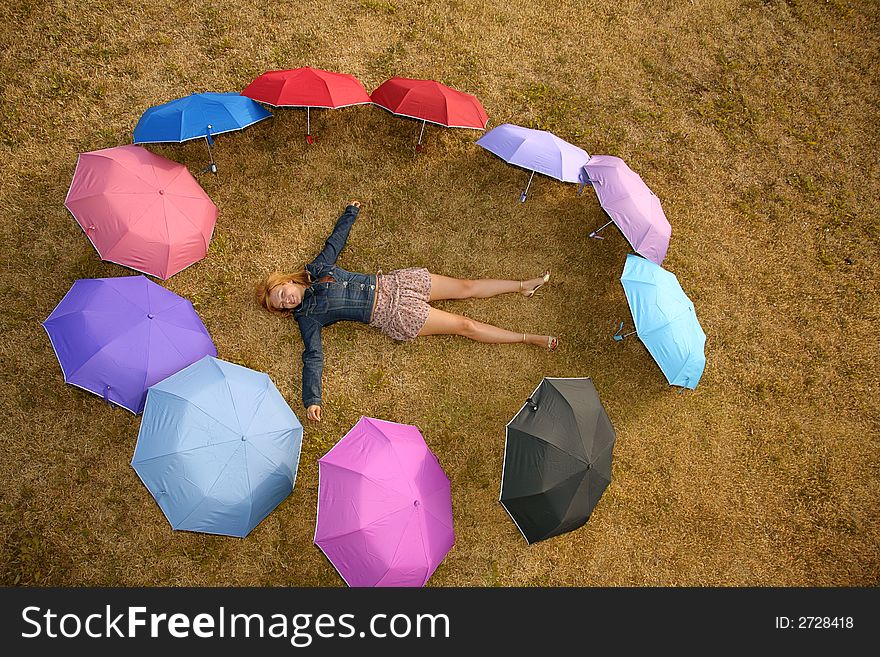Young woman lies on the grass at the ring from the umbrellas. Young woman lies on the grass at the ring from the umbrellas
