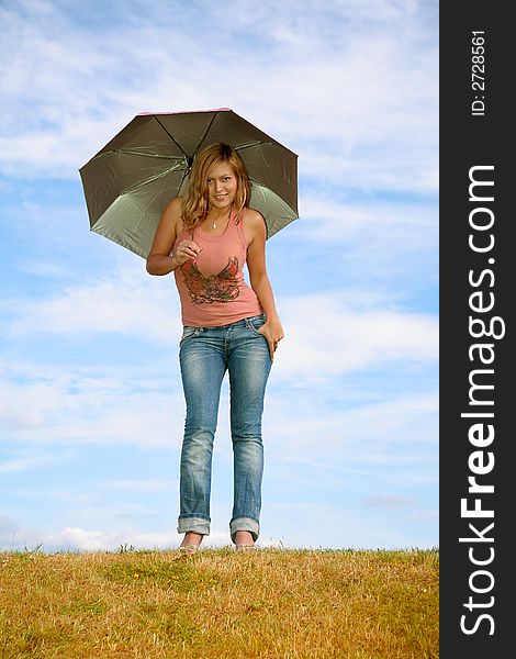 Young woman with the umbrella on to the meadow