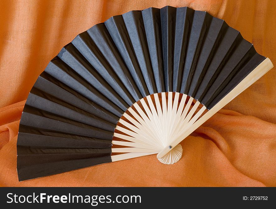 Traditional black paper fan on orange background. Traditional black paper fan on orange background