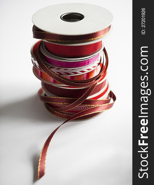 Stack of spools of holiday ribbons in red, white and gold on a white surface. selective focus. Stack of spools of holiday ribbons in red, white and gold on a white surface. selective focus