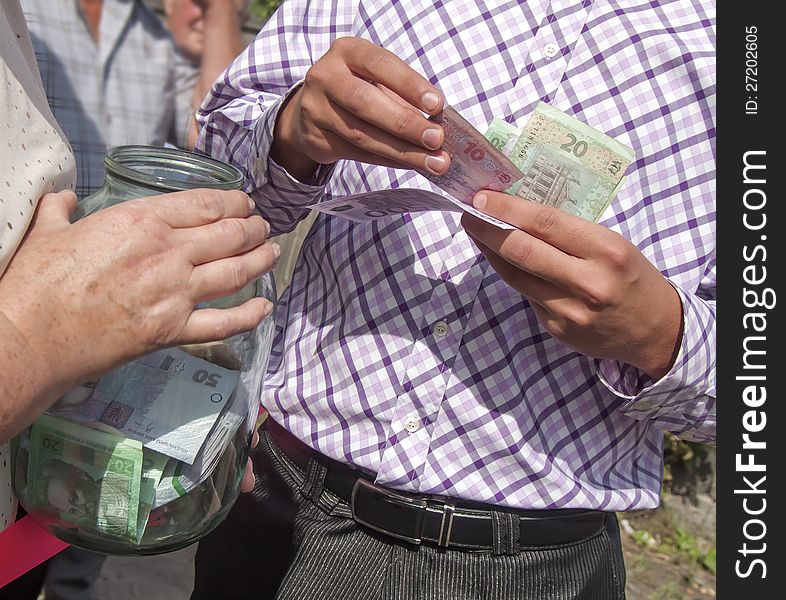 Man puts the money in a glass jar. Man puts the money in a glass jar