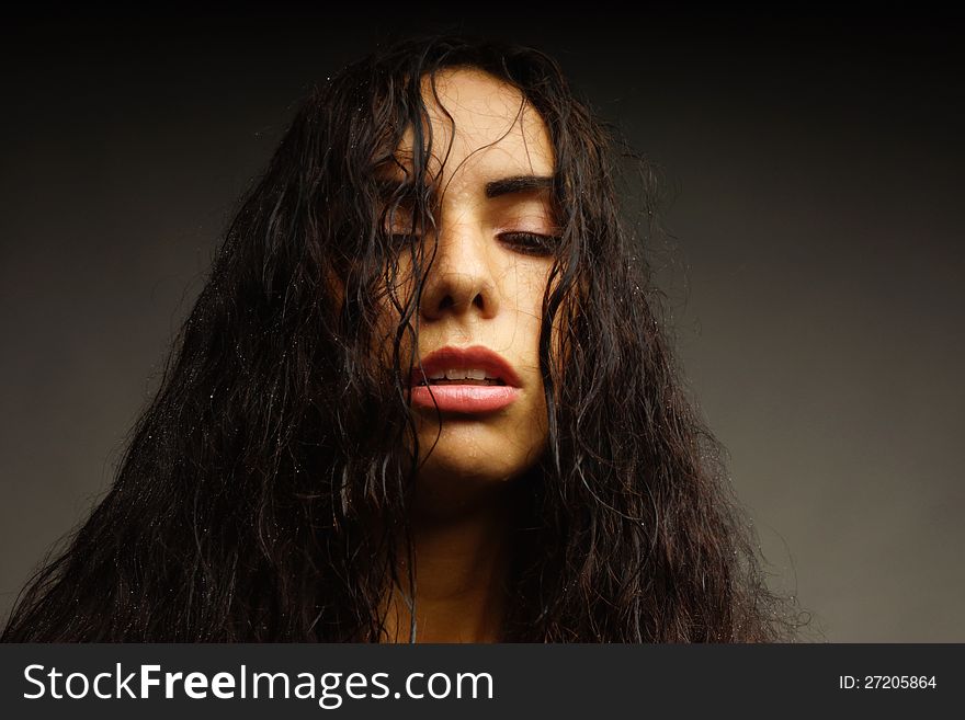 Portrait of a girl with wet hair and water on her face. Dark background.