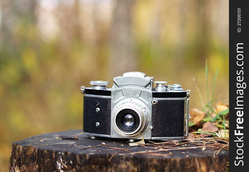 Old-fashioned vintage film camera on a tree stump. Old-fashioned vintage film camera on a tree stump