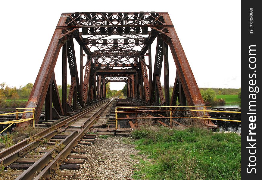 Old abandoned railroad bridge with rusty girders and tracks.  White space for copy or text. Old abandoned railroad bridge with rusty girders and tracks.  White space for copy or text.