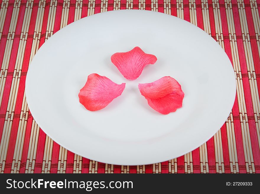 Arrangement of rose petals on a plate. On a red napkin.