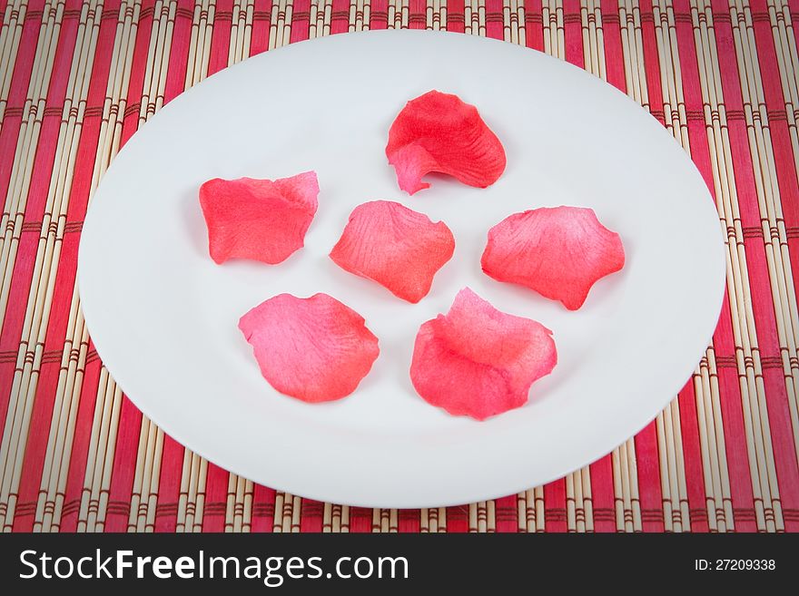 Set of rose petals on a plate. On a red background.