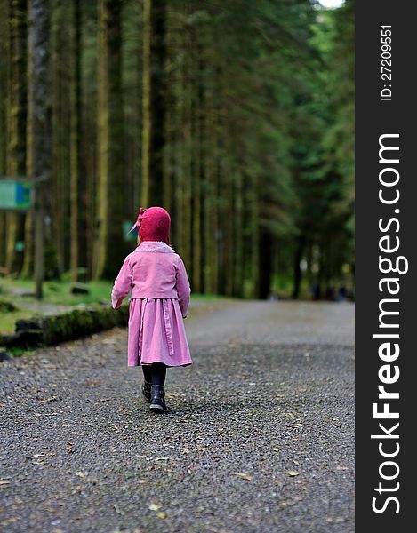 A little girl in a pink coat and hat in a forest. A little girl in a pink coat and hat in a forest.