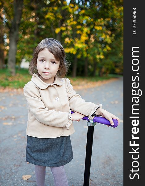 Preschooler girl outdoor in the park with scooter