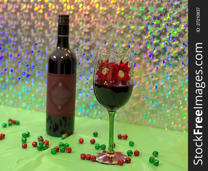 Red wine in a holiday wine glass with bottle of wine in back ground