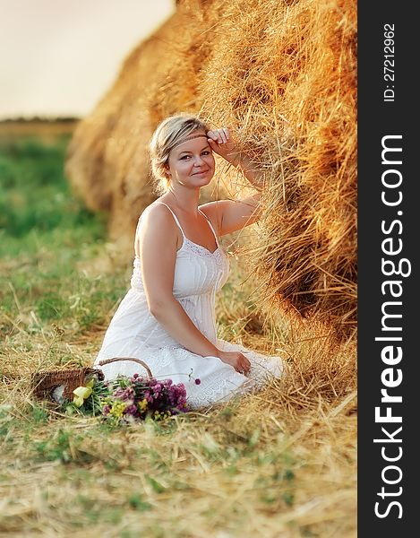 Beautiful girl with blond hair posing near the haystack. Beautiful girl with blond hair posing near the haystack