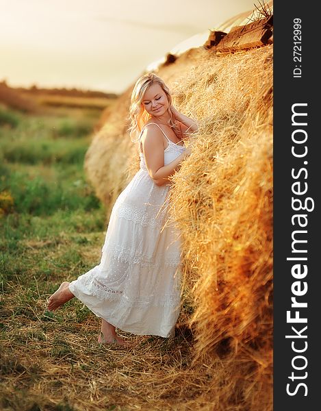 Beautiful girl with blond hair posing near the haystack. Beautiful girl with blond hair posing near the haystack