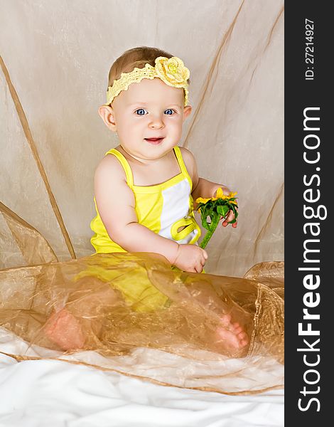 Beautiful little girl smiles and sits with yellow flower. Beautiful little girl smiles and sits with yellow flower