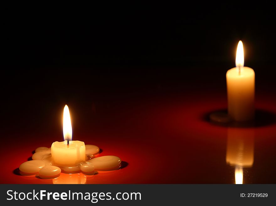 Separation. Two lighting candles on dark background with reflection